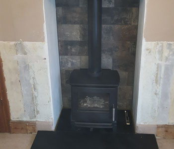 Hergom E30 XS Cast Iron Stove - with standard leg fitted by our installers with Riven slate hearth in Abinger between Guildford and Dorking in the Surrey Hills.